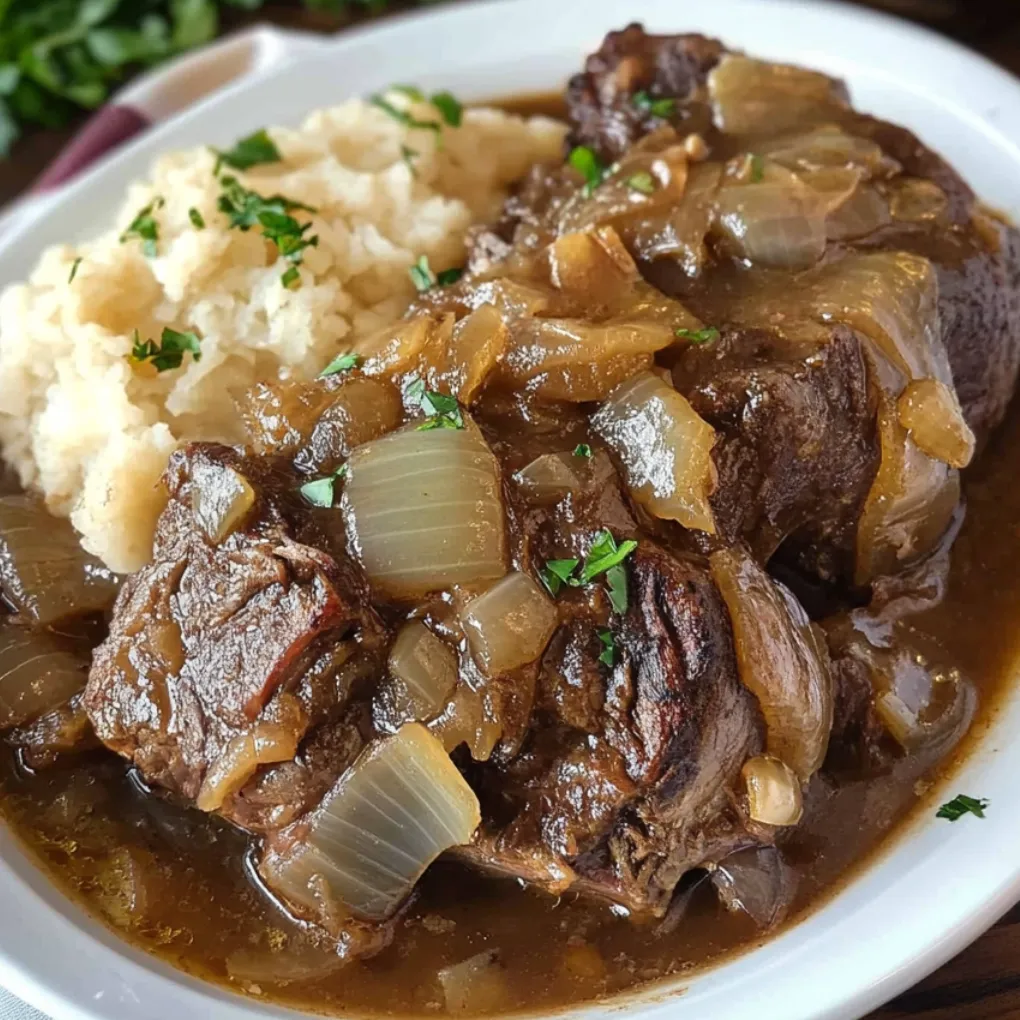 French onion pot roast cooked in an Instant Pot with caramelized onions and gravy, served over mashed potatoes.